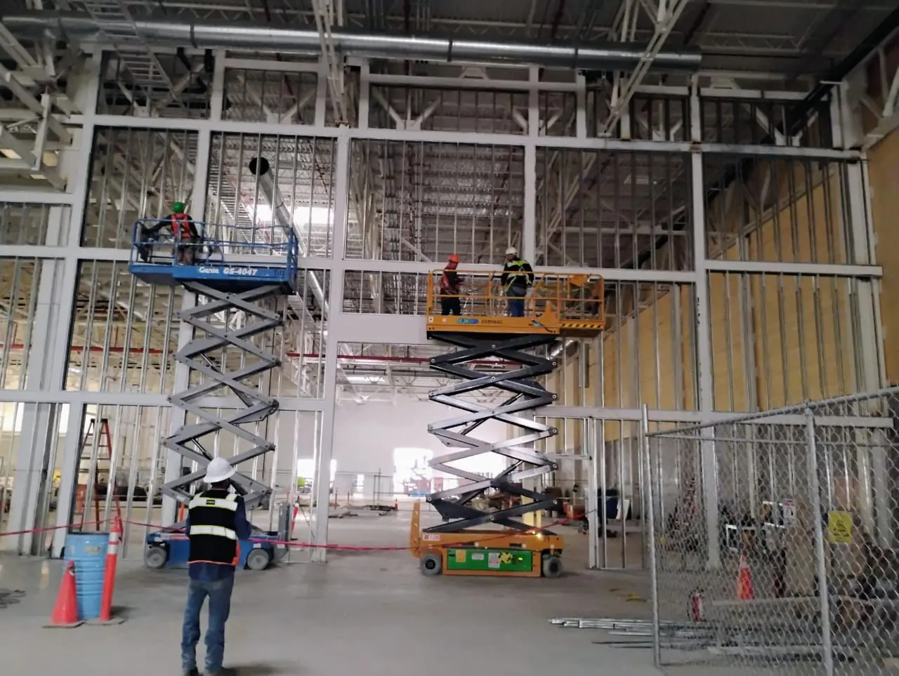 Técnicos sobre plataformas de tijera en estructura de nave