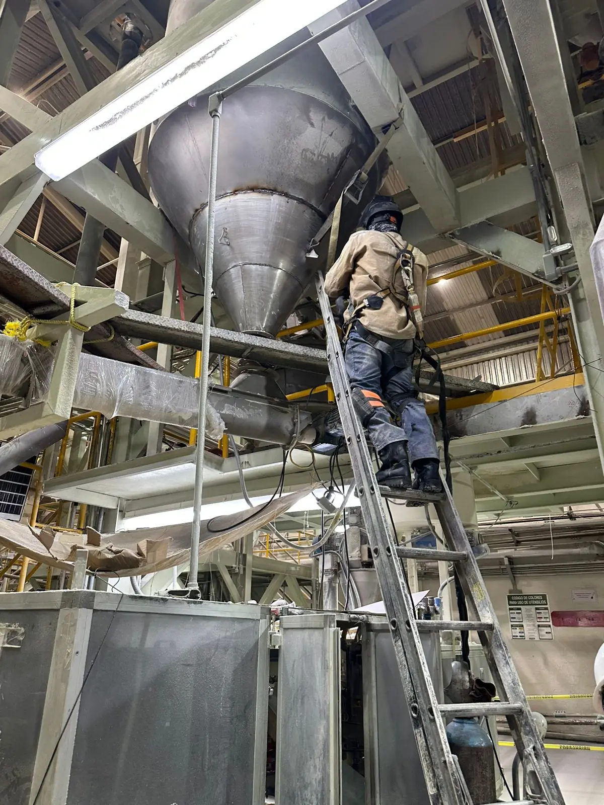 Técnico trabajando junto a una tolva de acero inoxidable